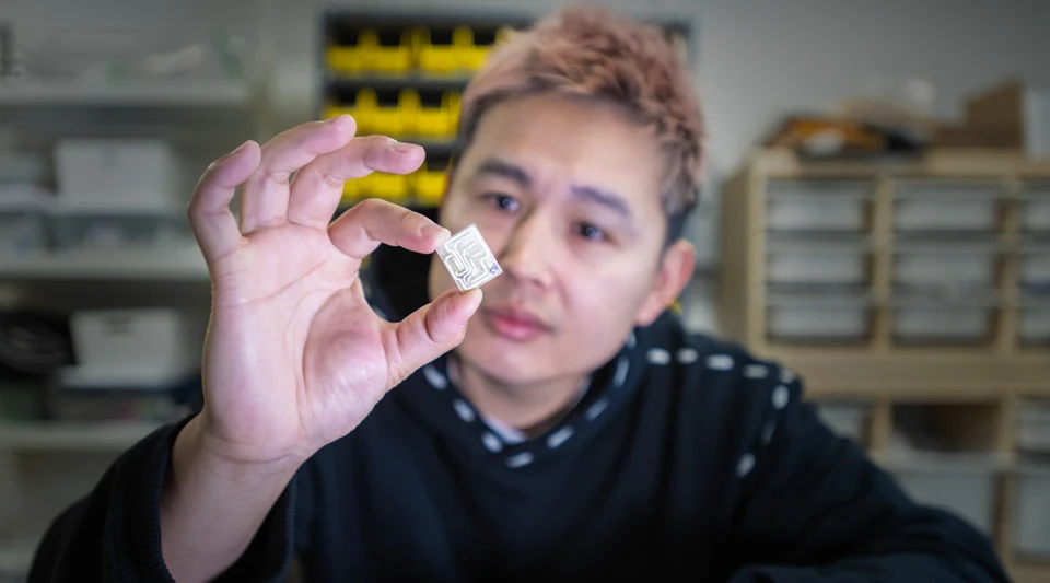Tingyu Cheng holding a biodegradable electronic chip in the lab
